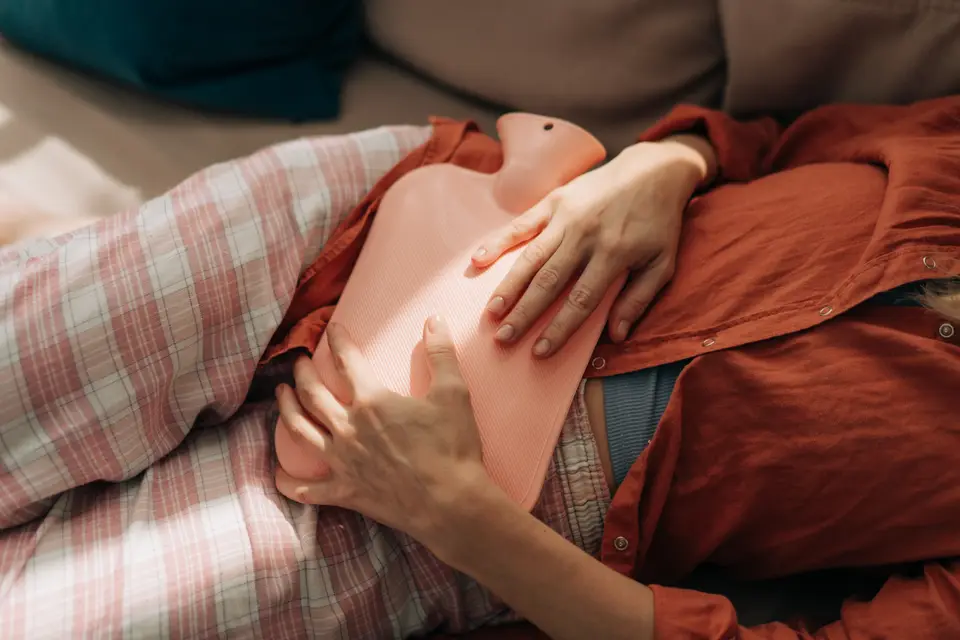 Femme allongée, une bouillotte posée sur le ventre